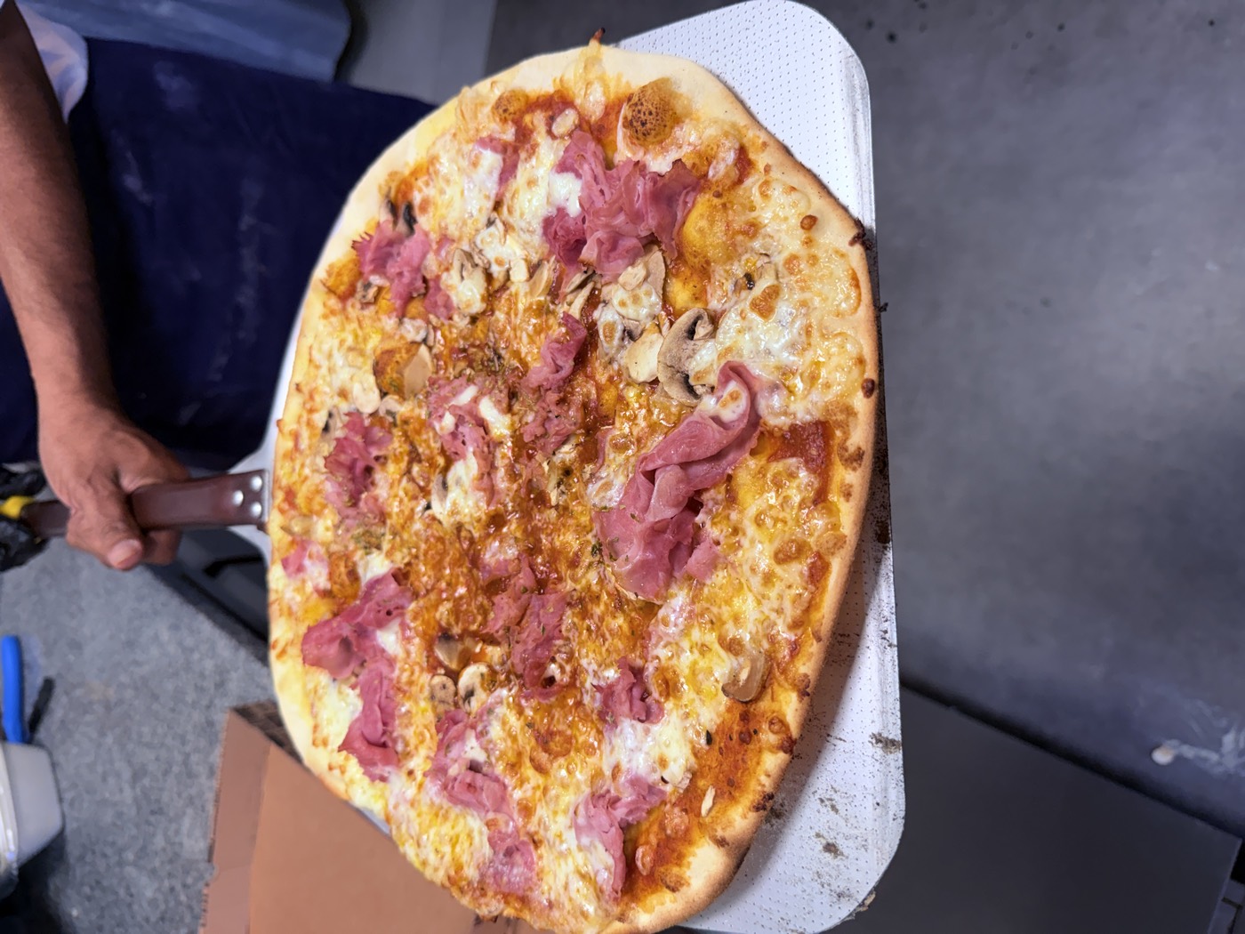 Pizza à emporter garnie de jambon et champignons, préparée à Sain-Bel par Sain Bellissima
